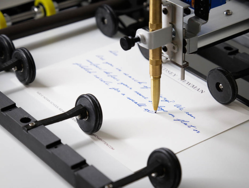 A Mozart Works robot writing a handwritten card with a real brass pen